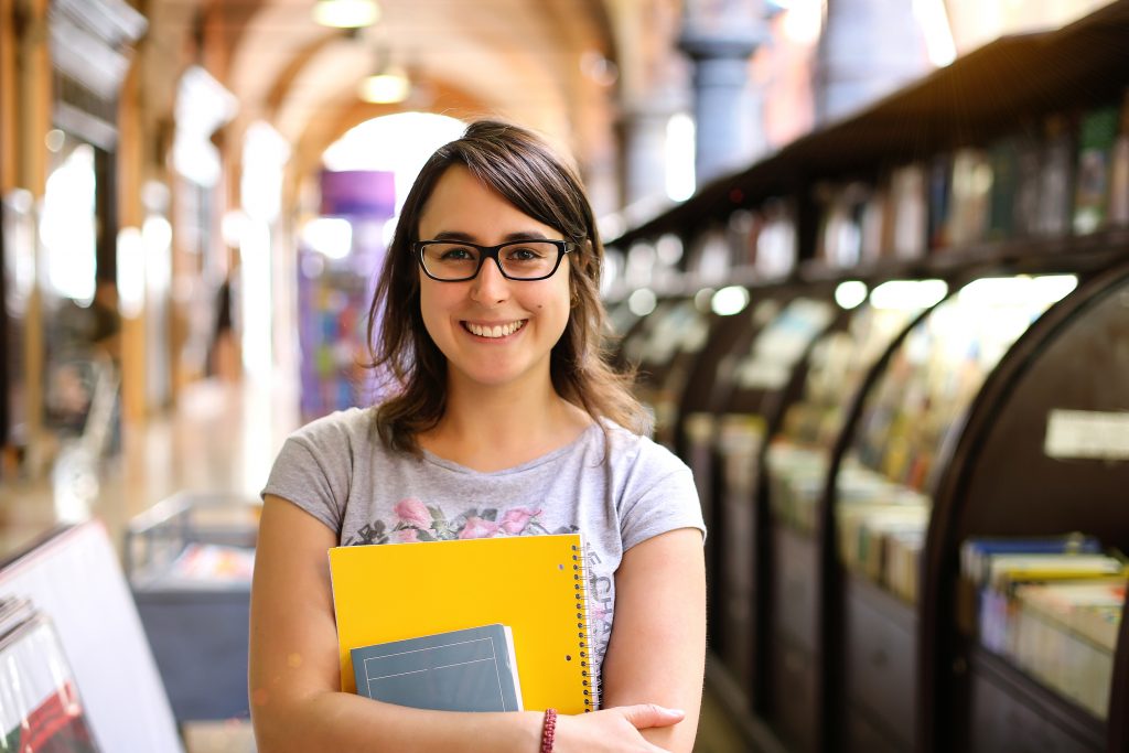 5 simple writing assignment tips high school girl in library with yellow notebook and book