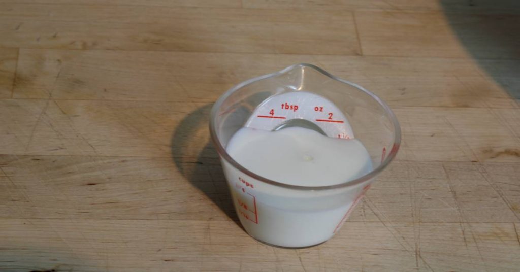 3 tablespoons of milk in small measuring cup for cheesy potatoes recipe.