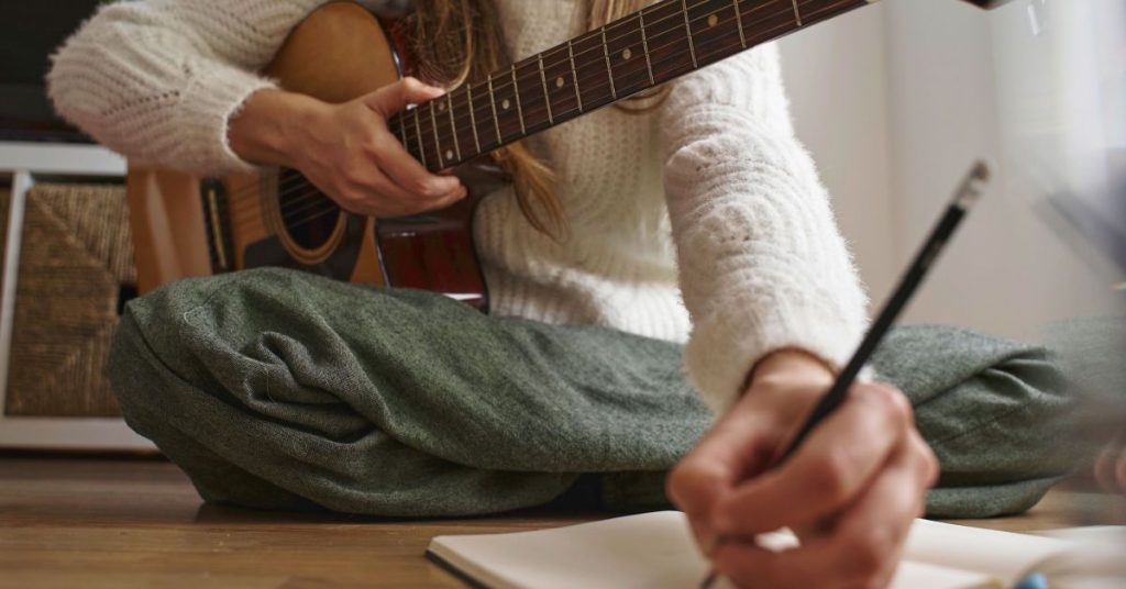 music scholarship girl with guitar writing on notebook