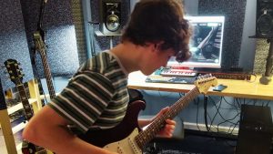 young man composing music on electric guitar